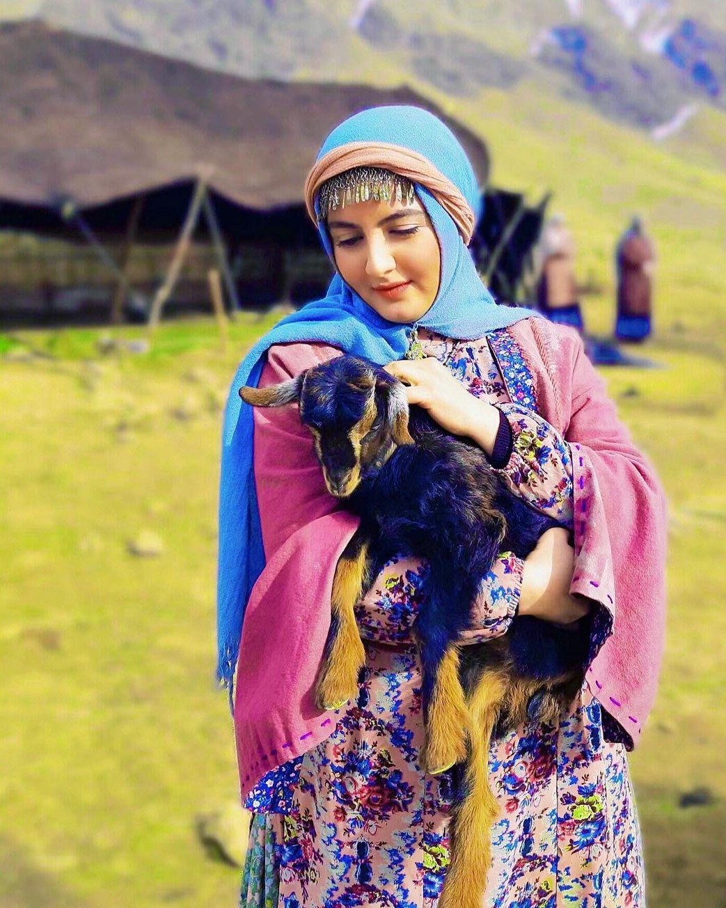 جهان پسند با لباس عشایری در حالی یک یک بز در آغوش دارد